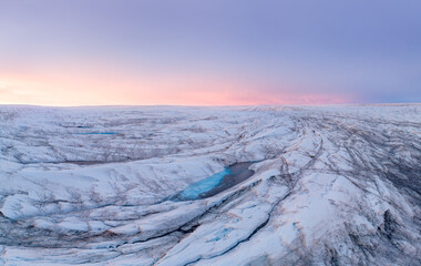 Blue glacier lakes on the Greenlandic ice cap shortly after sunset with epic sky