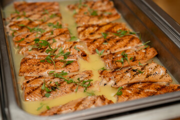 Salmon in garlic sauce in a metal catering dish being served at an event