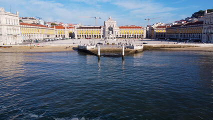 Naklejka premium Uma imagem icónica do Terreiro do Paço (também conhecido como Praça do Comércio), situada na Baixa Pombalina, em Lisboa. A ampla praça está rodeada por majestosos edifícios de cor amarela com arcadas 