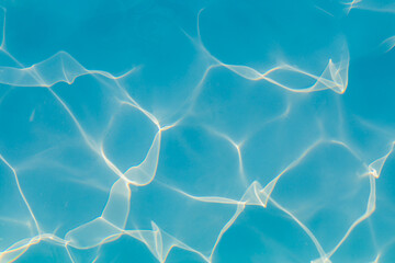 Close-up of vibrant blue swimming pool water with bright sunlight reflections creating dynamic, abstract patterns on the surface, evoking a sense of energy and freshness.