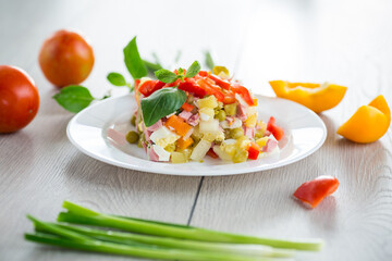 vegetable salad of boiled vegetables, with peas, sausage, sweet pepper. On a wooden table