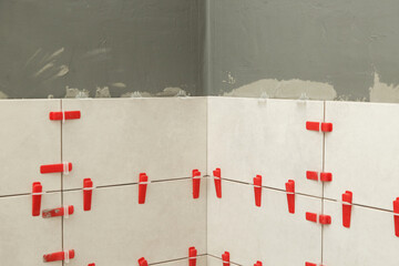 Flat wall plastic tile leveling system. Process of installation of tiles in the bathroom step by...