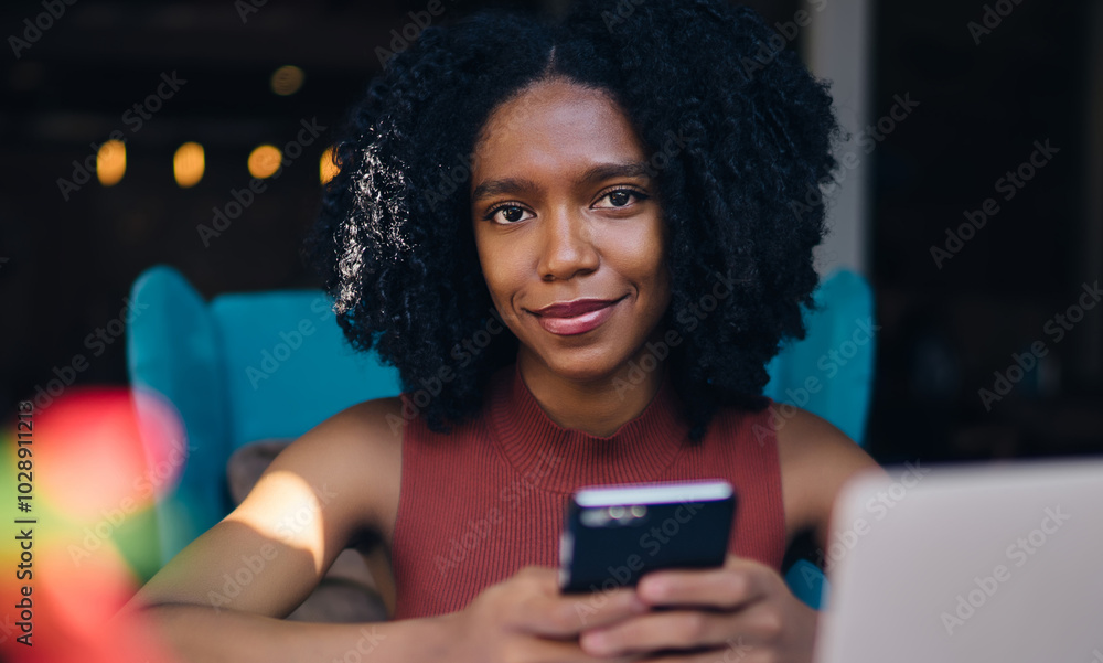Poster portrait of cheerful female blogger smiling at camera while sitting at table and spending time for c