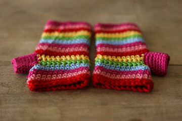 Colorful crochet gloves on a wooden background. Handmade.