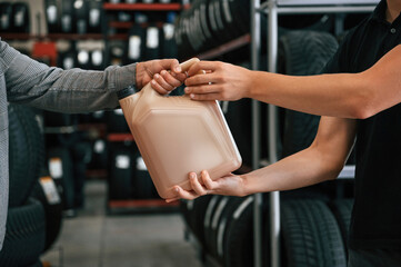 Hands of customer and seller, buying oil for the car in the tire fitting shop