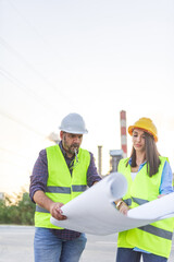 Two engineers reading blueprints on construction site
