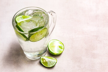 A glass of soda with slices of lime and ice with negative space