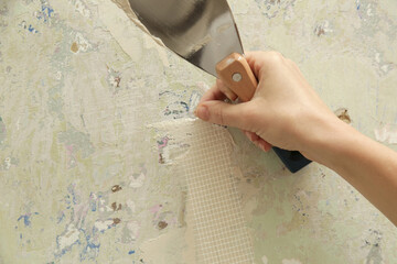 Woman plastering wall with putty-knife. Fixing wall surface and preparation for painting. DIY...