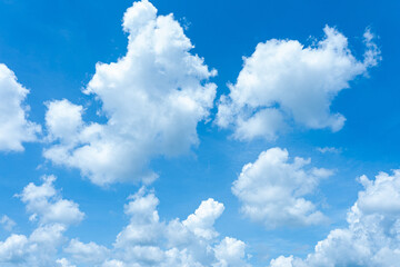 Fluffy cumulus clouds drift against a clear blue sky, casting soft shadows on the earth