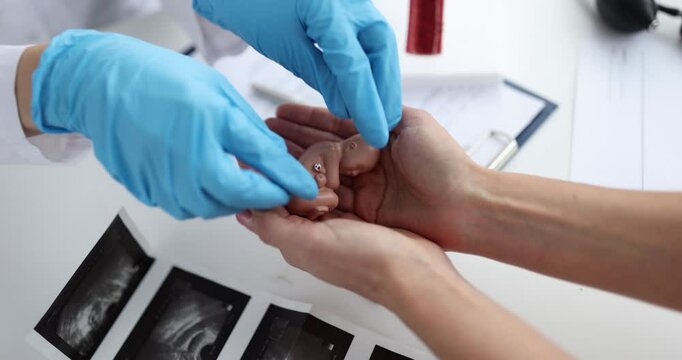 Gynecologist passes model of fetus to woman child. Abortions and their consequences concept