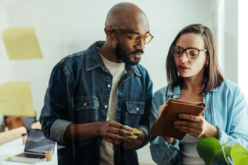 Colleagues discussing and collaborating while reviewing notes in a modern office