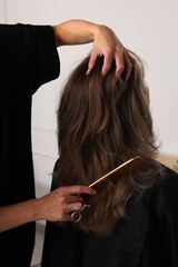 Fototapeta premium Hairdresser combing woman's hair in salon, closeup