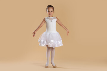 Naklejka premium Little ballerina practicing dance moves on beige background