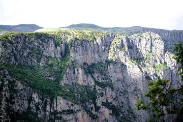 Naklejka premium Panoramic view over the steep and green cliffs of the Vikos Gorge in Epirus, Greece on a summer's day. The gorge in the Pindus Mountains is one of the deepest gorges in the world. Hiking in Greece