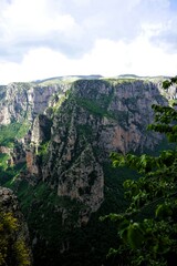 Naklejka premium Panoramic view over the steep and green cliffs of the Vikos Gorge in Epirus, Greece on a summer's day. The gorge in the Pindus Mountains is one of the deepest gorges in the world. Hiking in Greece