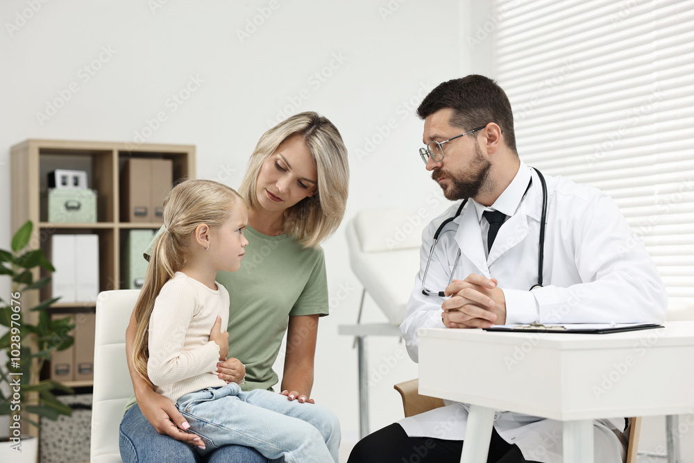 Wall mural Doctor consulting little girl with stomach pain and her mother in hospital