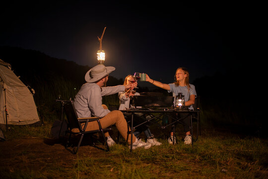 Family camping party with BBQ, and wine by the atmosphere is relaxed, capturing a moment of leisure enjoying a relaxed while sitting on folding chairs around a portable holiday camping.