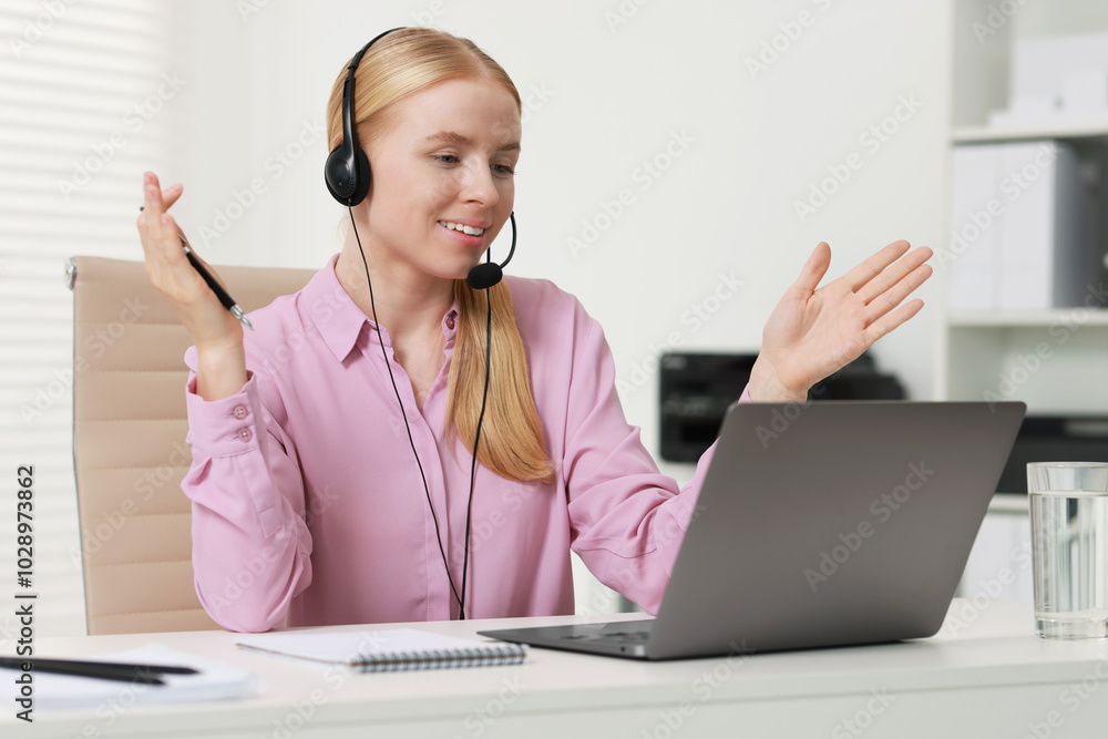 Poster interpreter in headset having video chat via laptop at table indoors