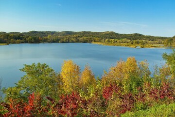 Beautiful Autumn landscape featuring colorful trees in front of a peaceful lake amid hills and forests near Galesville, Wisconsin, USA.