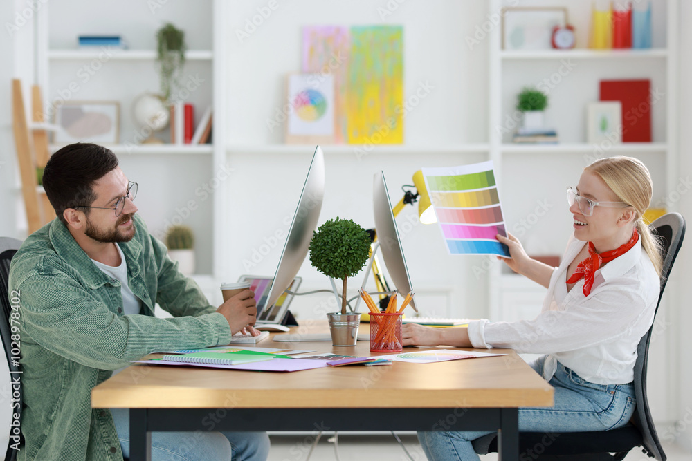 Poster designers with color palette working together at table in office