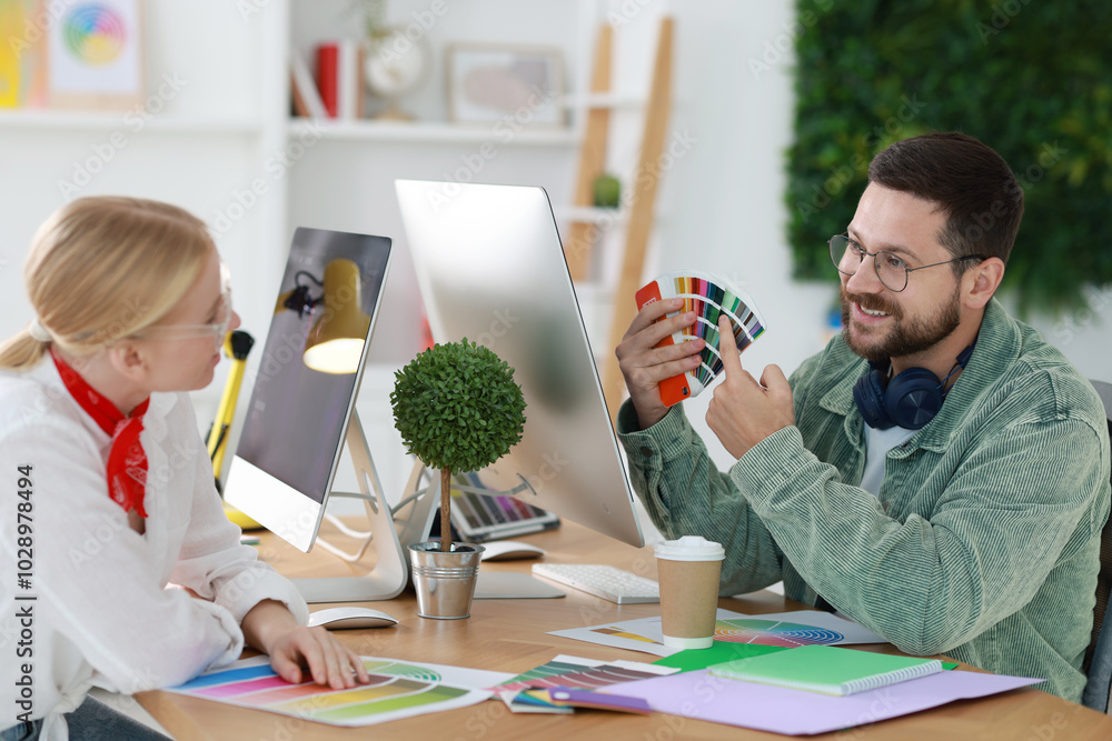 Poster designers with color samples working together at table in office