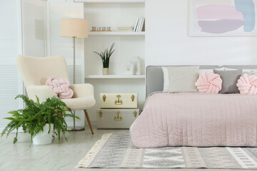 Large bed, houseplants and decorative elements in room. Stylish bedroom interior