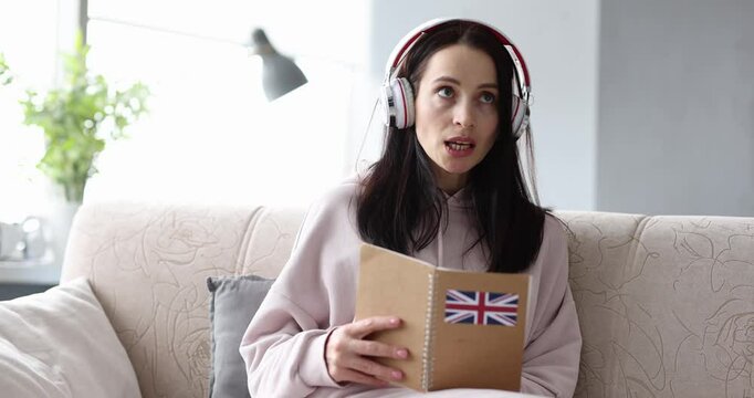 Woman in headphones is studying English at home sitting on couch. Audio lessons of foreign languages concept
