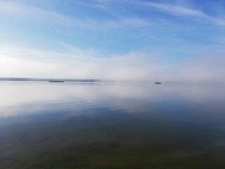 Shore of a misty lake at sunrise in summer.