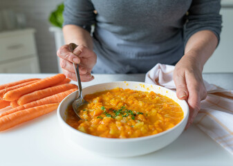 Woman serving bland food with easy to digest carrot potato soup in the kitchen