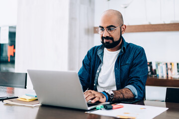 Obraz premium Bearded ethnic man working on laptop