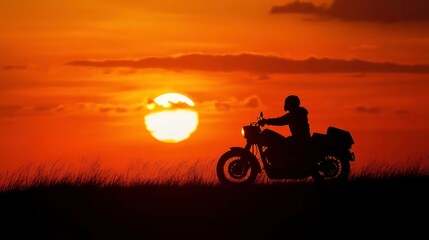 A lone motorcyclist rides into the sunset, silhouetted against the fiery sky.