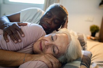 Senior couple cuddling peacefully in bed