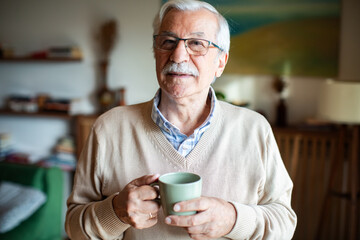 Happy senior man portrait holding coffee cup at home