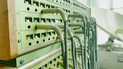 Close-up of a vintage telephone switchboard with numerous plug-in cables connected to numbered slots. Concept of old communication technology and manual telecommunications infrastructure