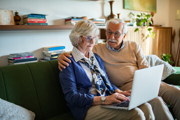 Senior couple using laptop together on couch at home