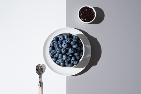 Ar&aacute;ndanos en un recipiente blanco y mermelada de ar&aacute;ndanos sobre un fondo gris y blanco. Vista superior	