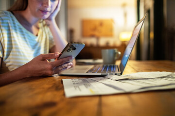 Woman late night working on laptop and smartphone at home