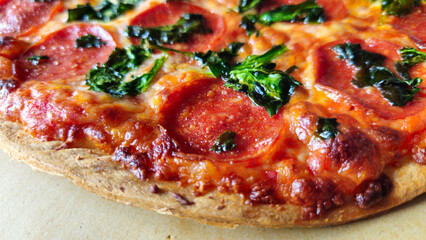 macro closeup of thin crust pepperoni pizza with spinach background