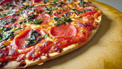macro closeup of pepperoni pizza with spinach on stone background