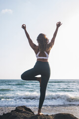 Back view of woman doing transitional tree posture for help move smoothly to other asanas, healthy...