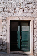 Stone old building with green wooden vintage door.