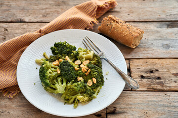 Sautéed broccoli with garlic on a white plate next to a checkered tablecloth on a rustic wooden table