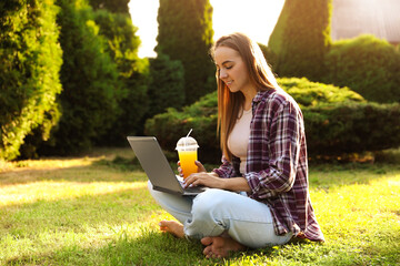 Woman using laptop on green lawn in park