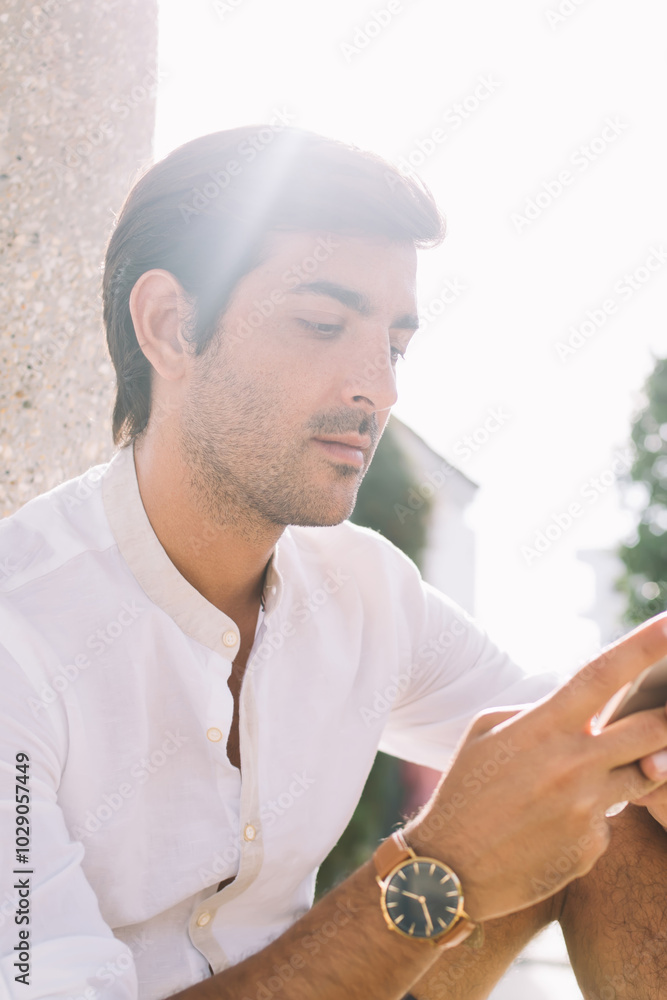 Poster young hindu hipster guy sitting at urban setting and searching information on website connected to 4