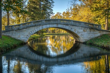 A serene stone bridge arches over a calm river, surrounded by lush trees reflecting in the water, creating a picturesque landscape.