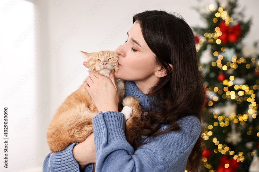 Poster Woman kissing her cute ginger cat in room decorated for Christmas