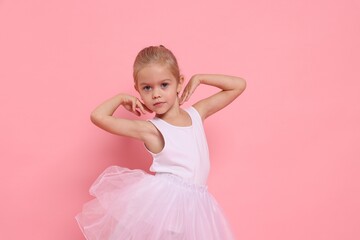 Little girl pretending to be ballerina on pink background. Dreaming of future profession