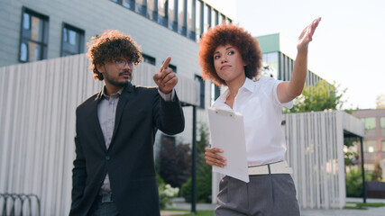 African American woman businesswoman showing building commercial property city skyscrapers company office urban to male client buyer investor walking Indian man Arabian businessman business discuss