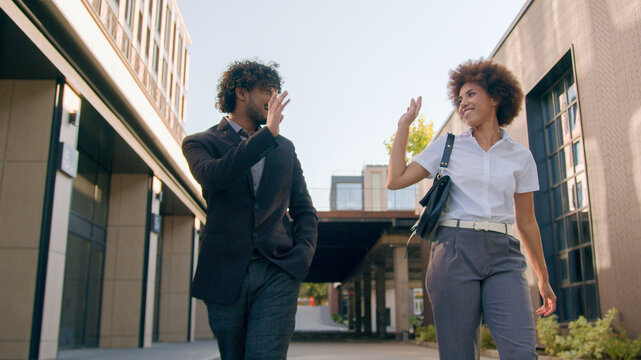 Two happy talking business colleagues business diverse multiracial coworkers Arabian businessman and African American businesswoman talking walking in city outdoors say bye goodbye together after work
