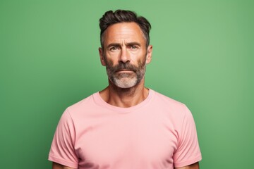 Fototapeta premium Portrait of a glad man in his 40s donning a trendy cropped top isolated in pastel green background